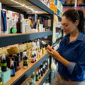 Shopper examining a personal care product label beside shelves of skin and hair care products.