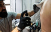 Tattoo artist spraying Calendula onto customers skin