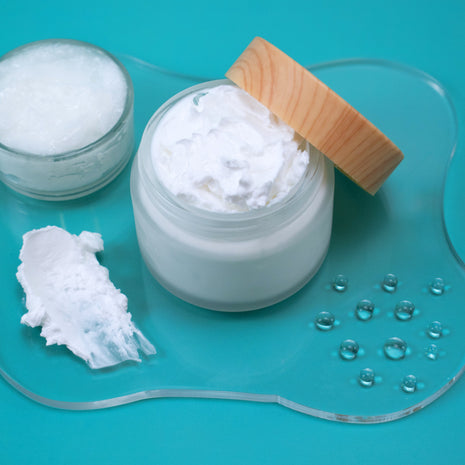 Jar of white cream with a wooden applicator on a blue background