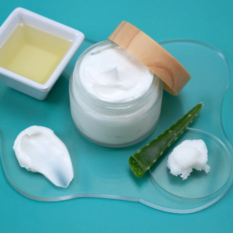 Jar of white cream with a wooden lid on a blue background