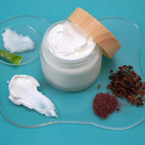 Jar of white cream with a wooden applicator on a blue background