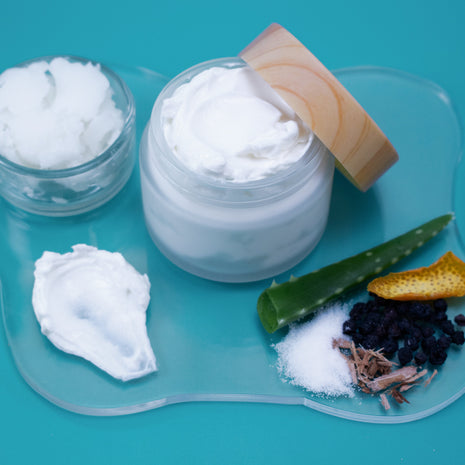 Jar of white cream with a wooden applicator on a blue background