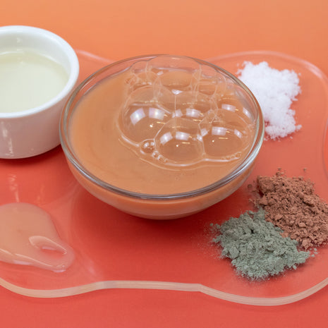 Clear container with brown powder on an orange surface
