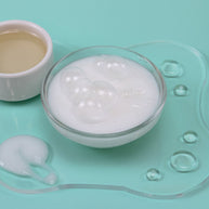 Glass bowl with white cream on a light blue background