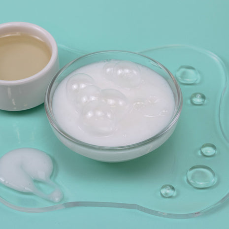 Glass bowl with white cream on a light blue background