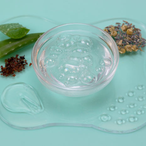 Clear glass bowl with textured surface on a light blue background with green leaves and dried herbs.