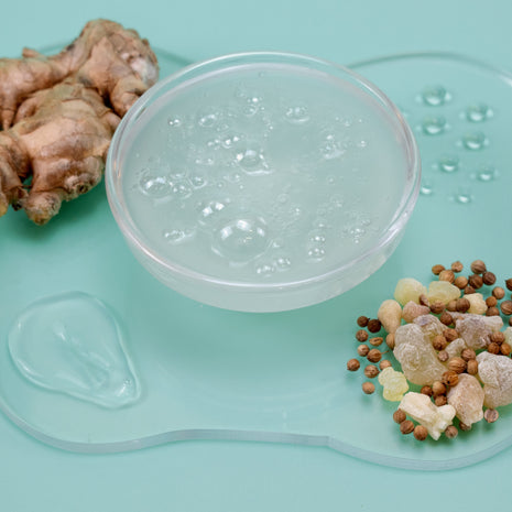 Clear gel-like substance in a mold with ginger root and spices on a light blue background