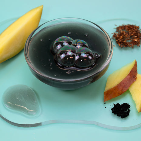 Bowl of dark liquid with slices of yellow fruit on a light blue background