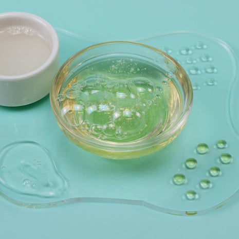 Clear dish with green gel-like substance on a light blue background