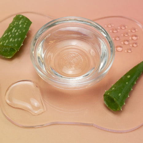 Simple Aloe Gel in a clear glass bowl with aloe vera leaves on a beige background