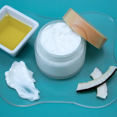 Jojoba Lotion with a cup of jojoba oil and coconut pieces on a blue background