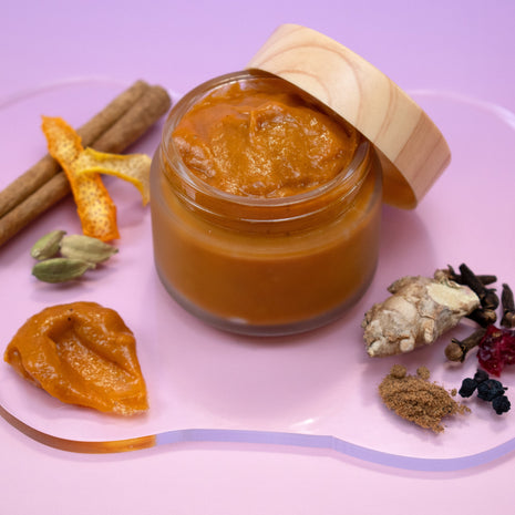 Jar of Pumpkin Mask with wooden lid on a pink plate with ganger, spices and dried fruits.