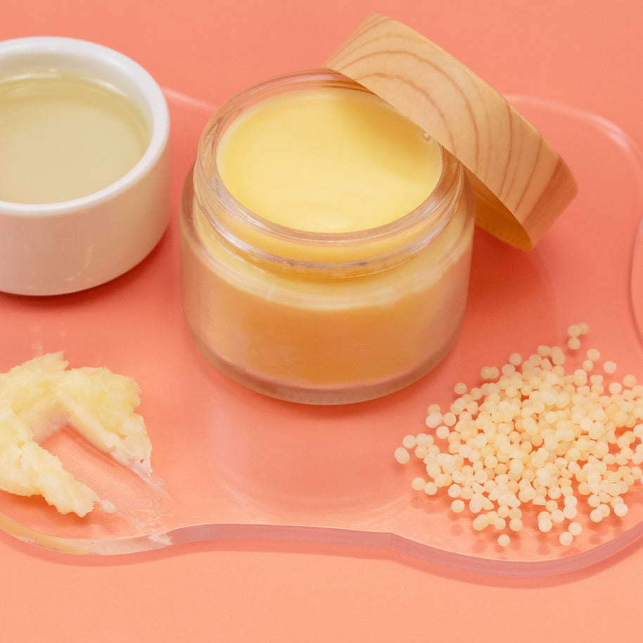 Jar of Perfume Balm with a wooden lid on a pink background