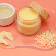 Jar of Perfume Balm with a wooden lid on a pink background