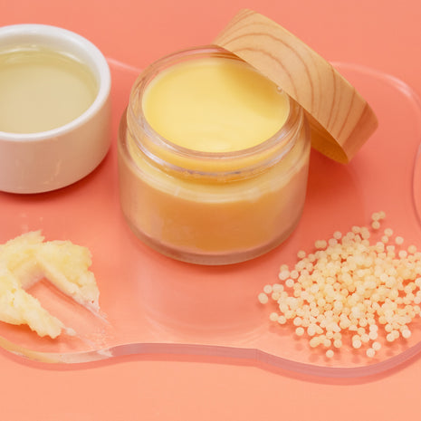 Jar of Perfume Balm with a wooden lid on a pink background