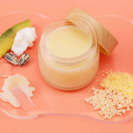 Jar of High Gloss Lip Balm with natural ingredients on a peach background