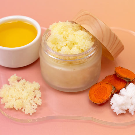 Jar of Turmeric & Neem Scrub with turmeric and neem on a pink background
