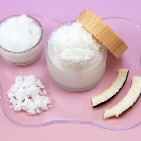 Jar of Virgin Coconut Sugar Scrub with a wooden lid on a pink background