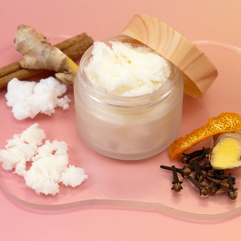 Jar of Gingerbread Sugar Scrub with wooden lid on a pink background with natural ingredients