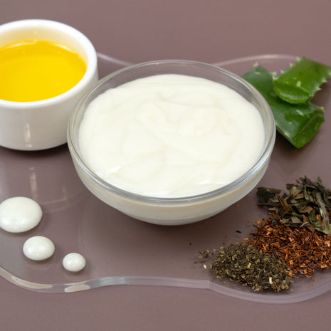 Bowl of Clarifying Facial Serum with oil, green leaves, and dried herbs on a brown surface