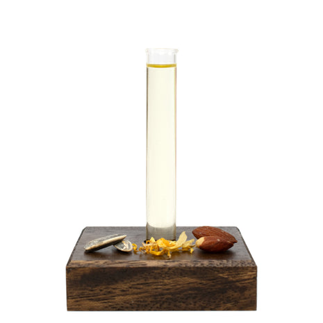 Bath & Body Oil in a glass holder on a wooden base with natural ingredients on a white background