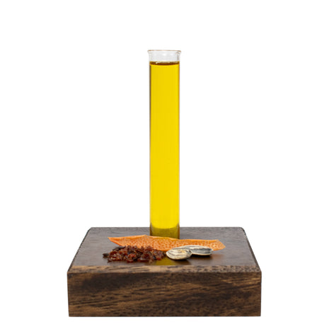 Glass beaker with Affirming Body & Hair Oil on a wooden block with spices and natural ingredients