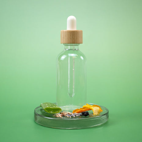 Clear glass dropper bottle of AHA Aftershave Splash with wooden cap on a green background