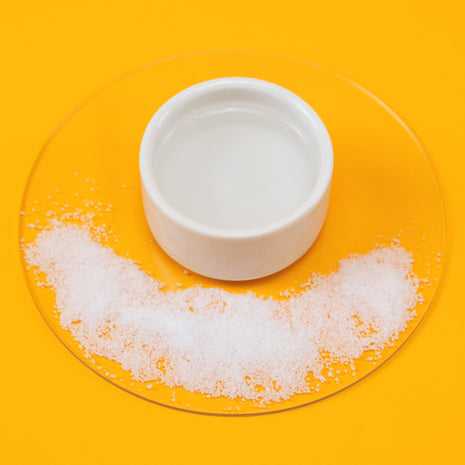 White bowl of Sea Salt Spray with a salt on a yellow background