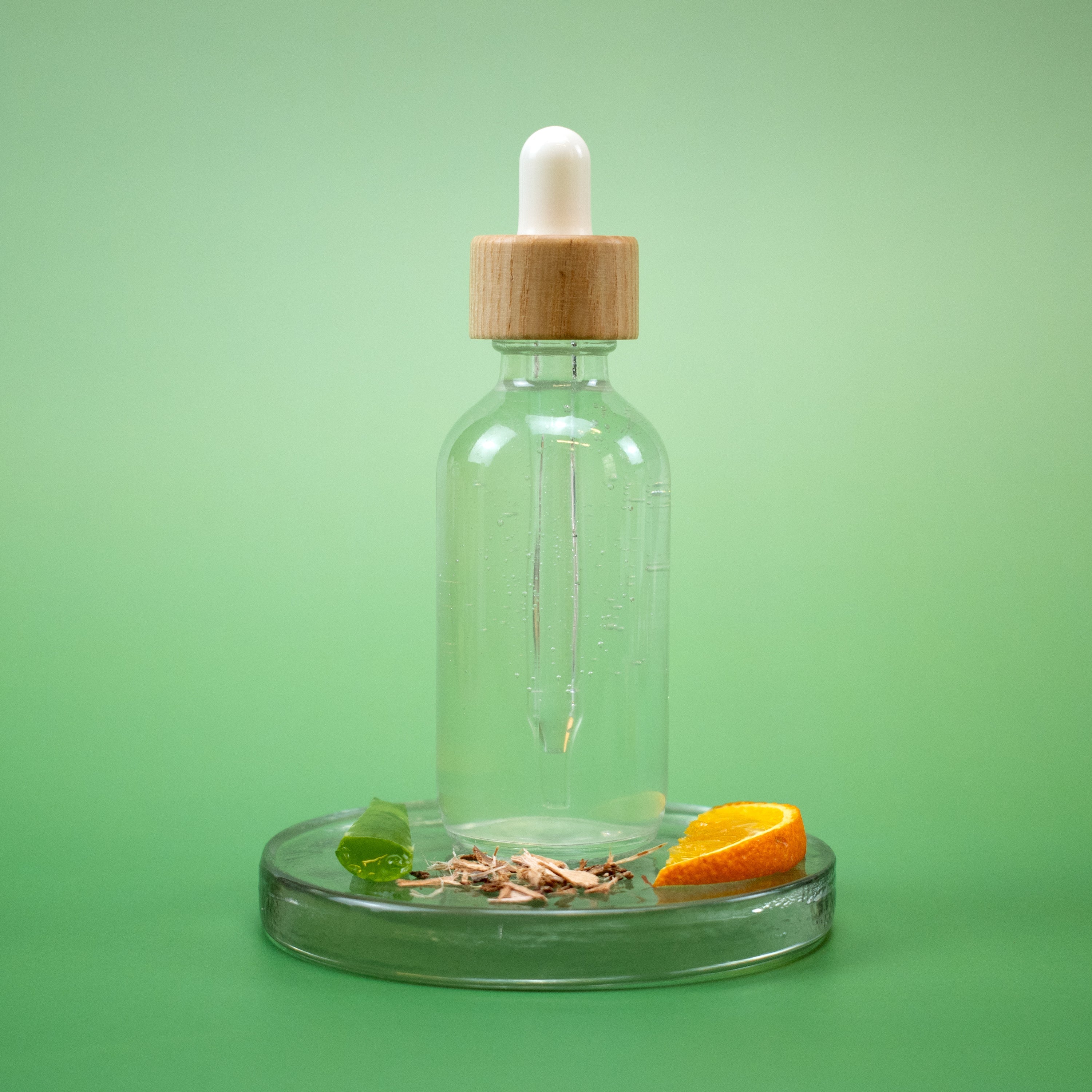 Calming Facial Toner in a clear glass dropper bottle with wooden cap with natural ingredients on a green background