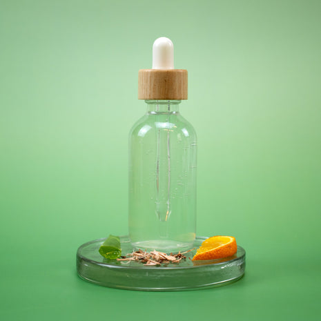 Calming Facial Toner in a clear glass dropper bottle with wooden cap with natural ingredients on a green background