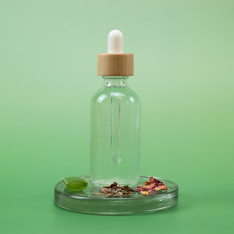 Moisturizing Facial Toner in a clear glass dropper bottle with wooden cap and natural ingredients on a green background