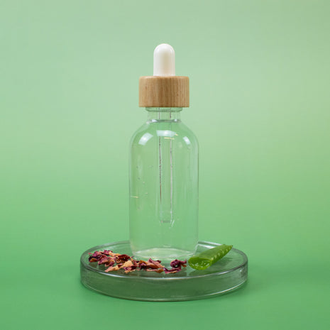 Rosewater Facial Toner in a clear glass dropper bottle with wooden cap and natural ingredients on a green background