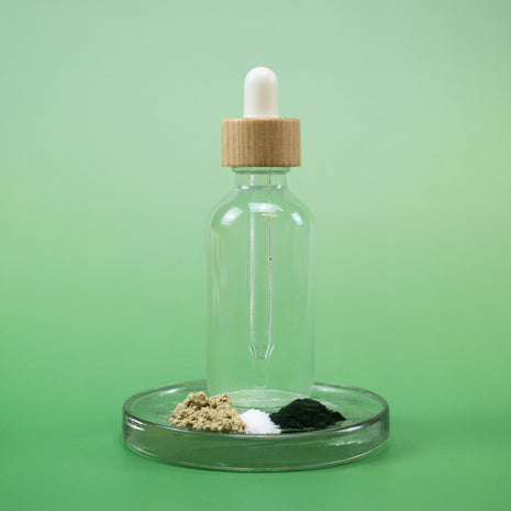 Sea Mineral Facial Toner in a clear glass dropper bottle with wooden cap and natural ingredients on a green background