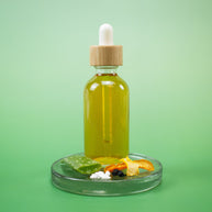 Vitamin C Facial Toner in a bottle with a dropper on a clear stand with natural ingredients against a green background