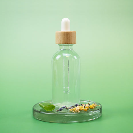 Herbal Tea Facial Toner in a clear glass dropper bottle with wooden cap and natural ingredients on a green background