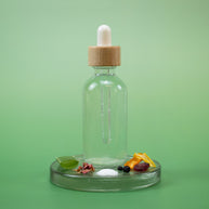 Mature Skin Facial Toner in a clear glass dropper bottle with wooden cap and natural ingredients on a green background