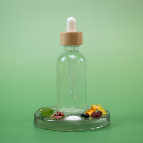 Mature Skin Facial Toner in a clear glass dropper bottle with wooden cap and natural ingredients on a green background