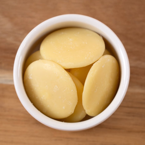 White bowl filled with Cocoa Butter Natural (Responsibly Grown) on a wooden surface