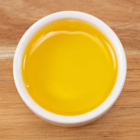 Jojoba Golden Oil (Responsibly Grown) in a white container on a wooden surface