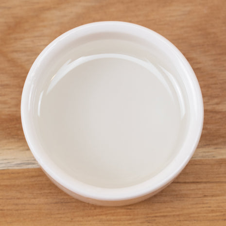 White ceramic bowl with Phenoxyethanol on a wooden surface