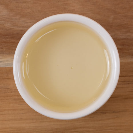 White cup filled with Meadowfoam Seed Oil (Refined) on a wooden surface