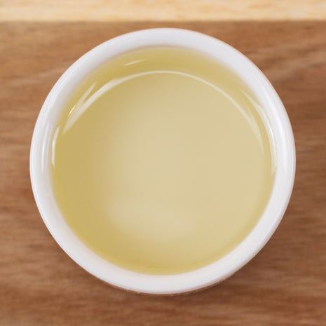 White cup filled with Castor Oil (Responsibly Grown) on a wooden surface