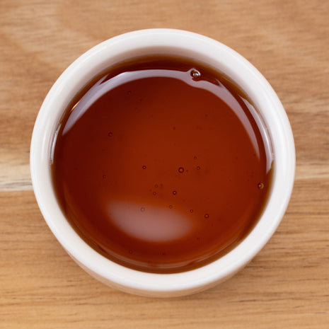 White bowl filled with Vitamin E Oil Natural Non GMO on a wooden surface