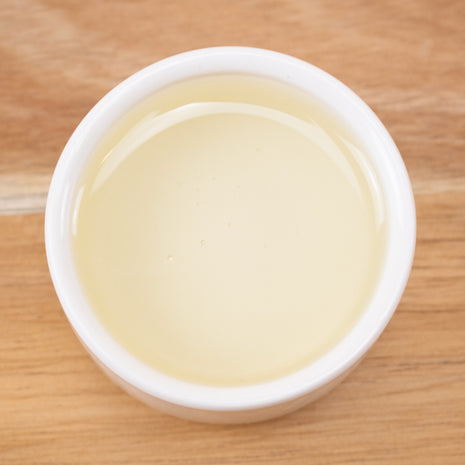 White cup filled with Tetrasodium Glutamate Diacetate on a wooden surface