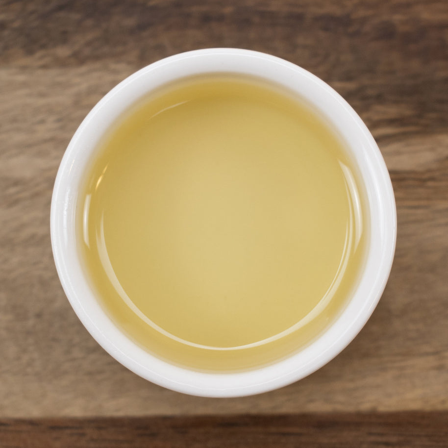 White cup filled with Argan Oil (Responsibly Grown) on a wooden surface