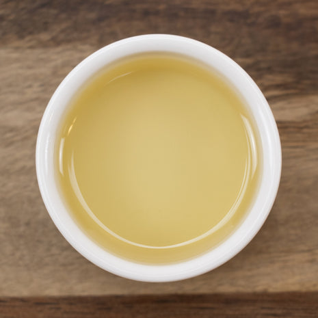 White cup filled with Argan Oil (Responsibly Grown) on a wooden surface