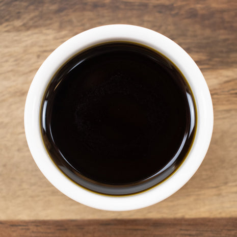 White bowl filled with Rosemary CO2 Extract (Responsibly Grown) on a wooden surface