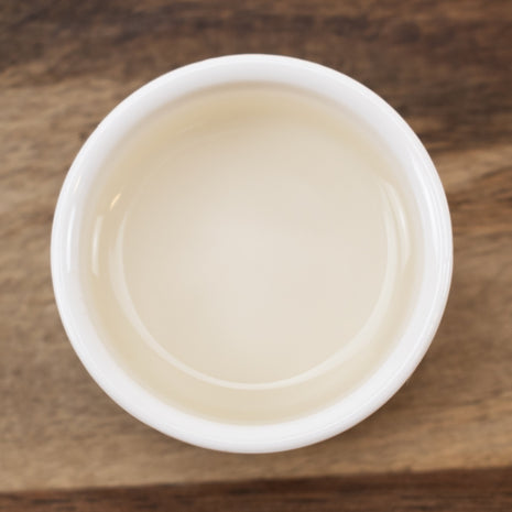 White container with Orange Blossom Water (Neroli Distillate) on a wooden surface
