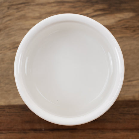 White ceramic bowl with Rose Distillate Bulgarian on a wooden surface