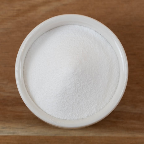 Niacinamide (Vitamin B3) in a small white container on a wooden surface